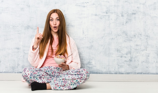 Foto junge kaukasische frau, die eine müslischüssel hat etwas großartige idee hält