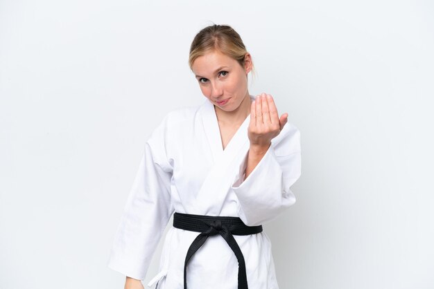 Junge kaukasische Frau, die Karate isoliert auf weißem Hintergrund macht und einlädt, mit der Hand zu kommen Glücklich, dass du gekommen bist