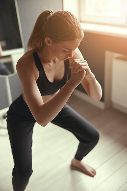 Junge kaukasische Frau, die Morgensportübungen zu Hause macht