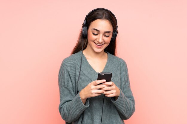 Junge kaukasische Frau, die Musik hört und auf Handy schaut