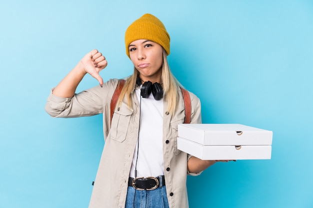 Junge kaukasische Frau, die Pizzen lokalisiert zeigt, die eine Abneigungsgeste zeigen, Daumen nach unten. Uneinigkeit Konzept.