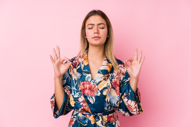 Junge kaukasische Frau, die Pyjamas trägt, entspannt sich nach hartem Arbeitstag, sie führt Yoga durch.