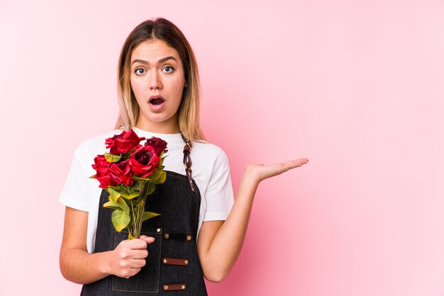 Junge kaukasische Frau, die Rosen hält, beeindruckte, die Leerzeichen auf Handfläche halten.