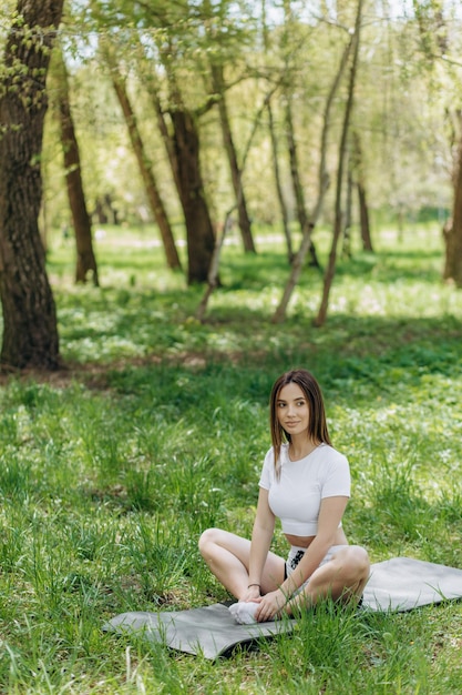 Junge kaukasische Frau, die Yogaübungen im Sommerstadtpark tut