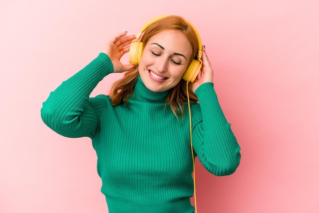 Junge kaukasische Frau hört Musik isoliert auf rosa Hintergrund