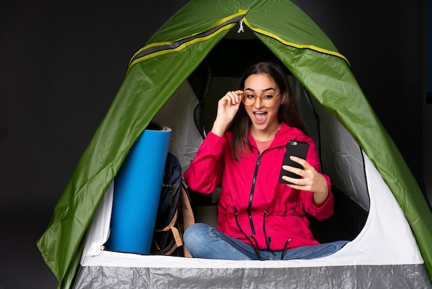 Junge kaukasische Frau in einem kampierenden grünen Zelt, das ein selfie macht