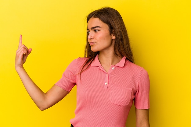 Foto junge kaukasische frau isoliert auf gelbem hintergrund, die mit dem finger auf sie zeigt, als ob sie einladen würde, näher zu kommen.