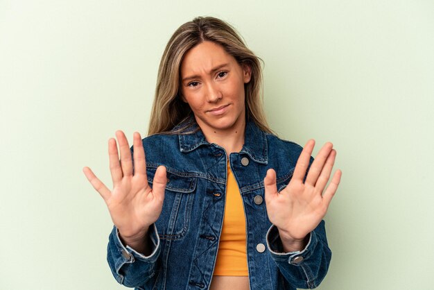 Foto junge kaukasische frau isoliert auf grünem hintergrund, die jemanden ablehnt, der eine geste des ekels zeigt.