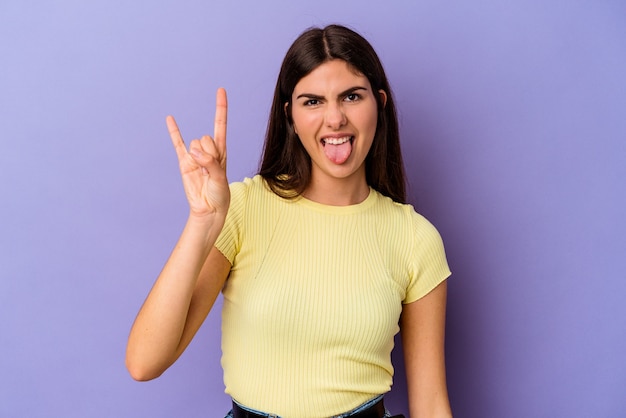 Junge kaukasische Frau isoliert auf lila Hintergrund, die Rockgeste mit den Fingern zeigt showing