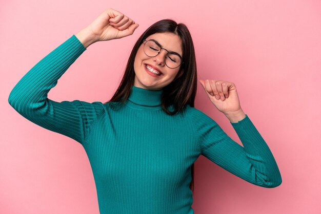 Junge kaukasische Frau isoliert auf rosa Hintergrund, die einen besonderen Tag feiert, springt und hebt die Arme mit Energie