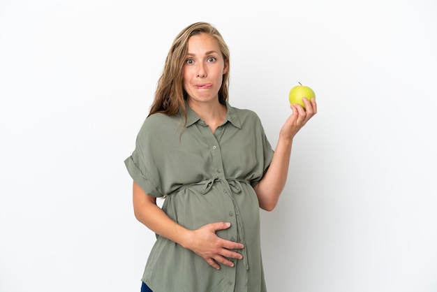Junge kaukasische Frau isoliert auf weißem Hintergrund schwanger und hält einen Apfel