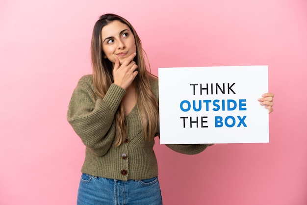 Junge kaukasische Frau isoliert mit einem Plakat mit Text Think Outside The Box und Thinking