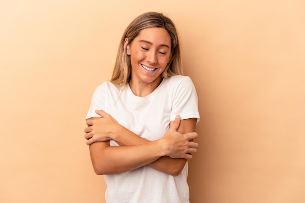 Junge kaukasische Frau lokalisiert auf beige Hintergrund, die lacht und Spaß hat.