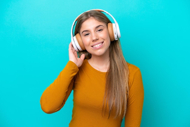 Junge kaukasische Frau lokalisiert auf blauem Hintergrund, der Musik hört