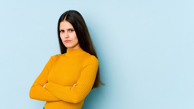 Junge kaukasische Frau lokalisiert auf blauer Wand verdächtig, unsicher, Sie untersuchend.