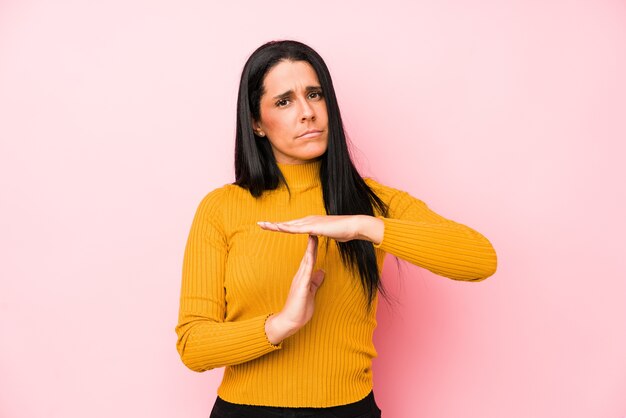 Junge kaukasische Frau lokalisiert auf einer rosa Wand, die eine Zeitüberschreitungsgeste zeigt.