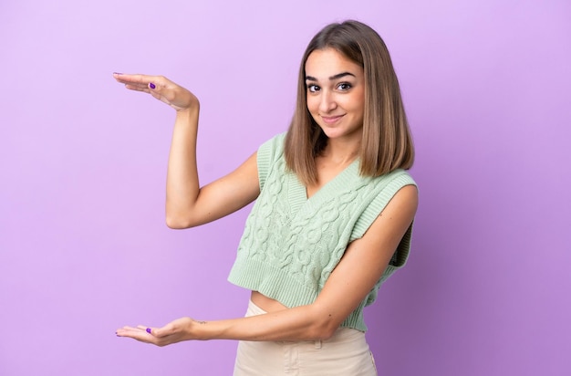 Junge kaukasische Frau lokalisiert auf purpurrotem Hintergrund, der copyspace hält, um eine Anzeige einzufügen