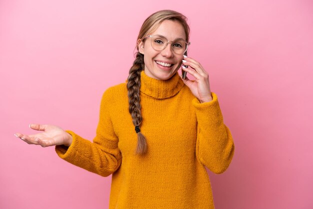 Foto junge kaukasische frau lokalisiert auf rosa hintergrund, die ein gespräch mit dem handy mit jemandem hält