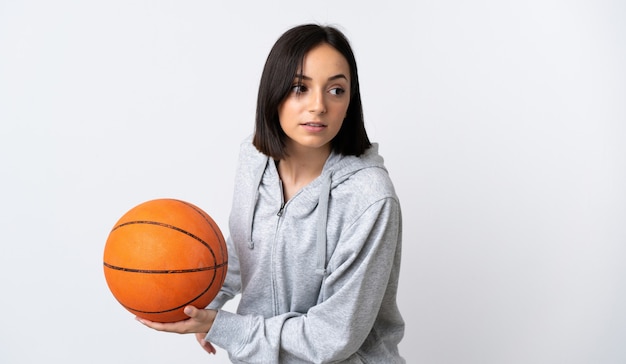 Junge kaukasische Frau lokalisiert auf weißem Basketball spielen