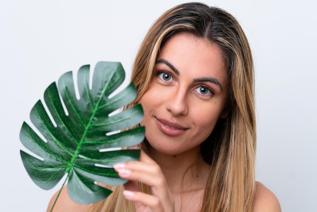 Junge kaukasische Frau lokalisiert auf weißem Hintergrund, der ein Palmblatt hält Close up Portrait