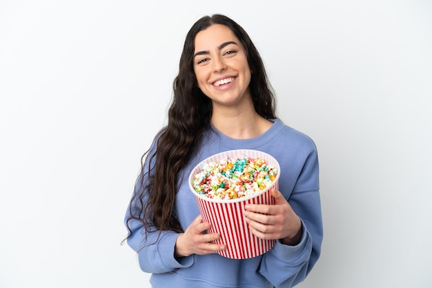 Junge kaukasische Frau lokalisiert auf weißem Hintergrund, der einen großen Eimer Popcorn hält