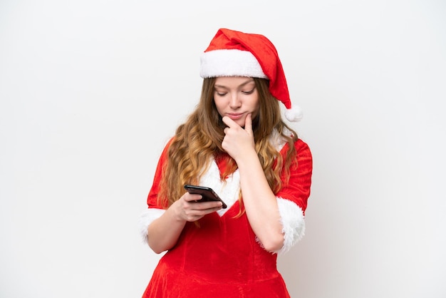 Junge kaukasische Frau mit dem Weihnachtskleid lokalisiert auf weißem Hintergrund, der denkt und eine Nachricht sendet