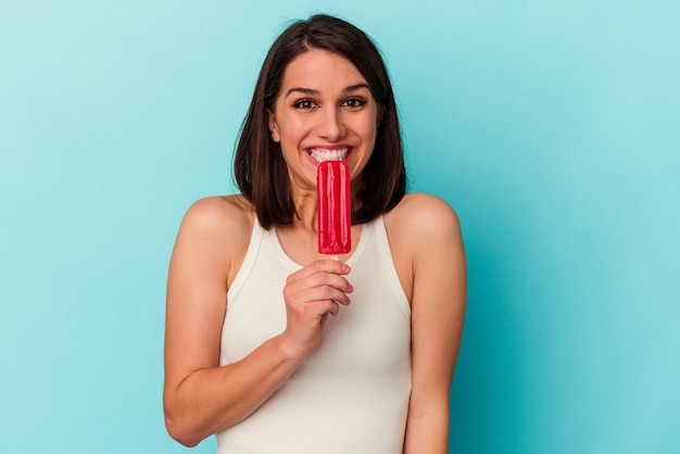 Junge kaukasische Frau mit einem Eis auf blauem Hintergrund isoliert