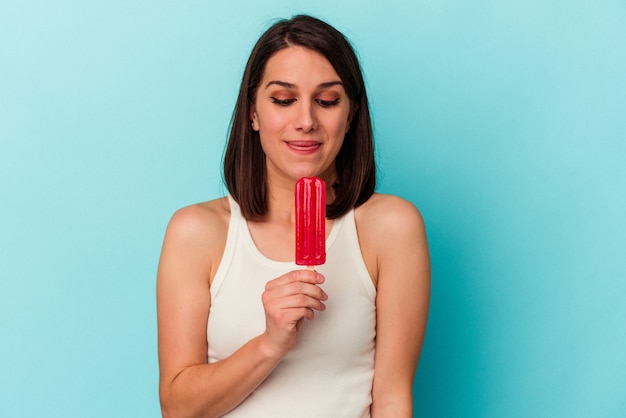 Junge kaukasische Frau mit einem Eis auf blauem Hintergrund isoliert