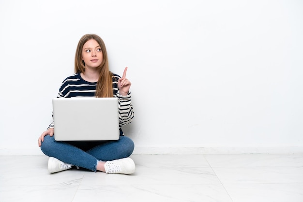 Junge kaukasische Frau mit einem Laptop, der auf dem Boden sitzt