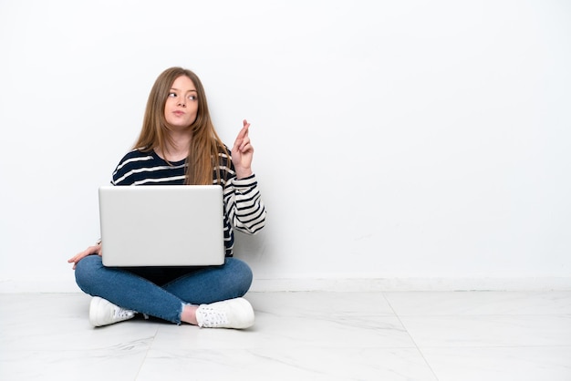 Junge kaukasische Frau mit einem Laptop, der auf dem Boden sitzt