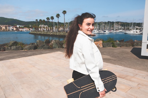 Junge kaukasische Frau mit einem Longboard am Meer