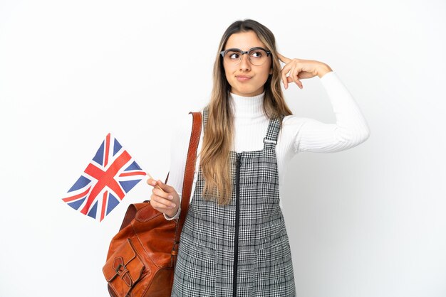 Junge kaukasische Frau mit einer Flagge des Vereinigten Königreichs isoliert auf weißem Hintergrund mit Zweifeln und Denken