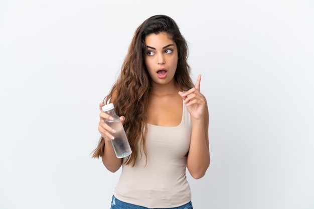 Junge kaukasische Frau mit einer Flasche Wasser isoliert auf weißem Hintergrund, die eine Idee denkt und mit dem Finger nach oben zeigt