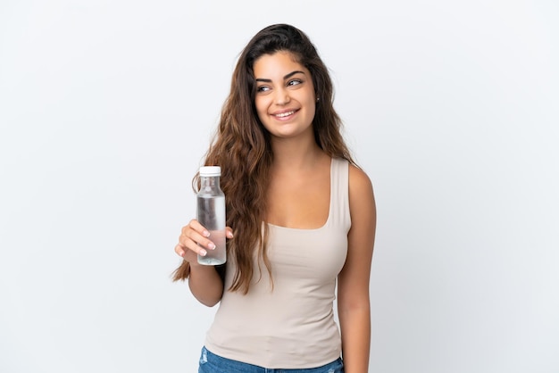 Junge kaukasische Frau mit einer Flasche Wasser lokalisiert auf weißem Hintergrund, die eine Idee beim Nachschlagen denkt