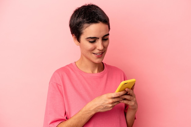 Junge kaukasische Frau mit Handy isoliert auf rosa Hintergrund