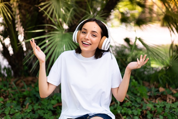 Junge kaukasische Frau mit Kopfhörern im Freien, die viel lächeln