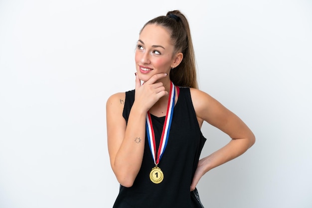 Junge kaukasische Frau mit Medaillen lokalisiert auf weißem Hintergrund, der zur Seite schaut