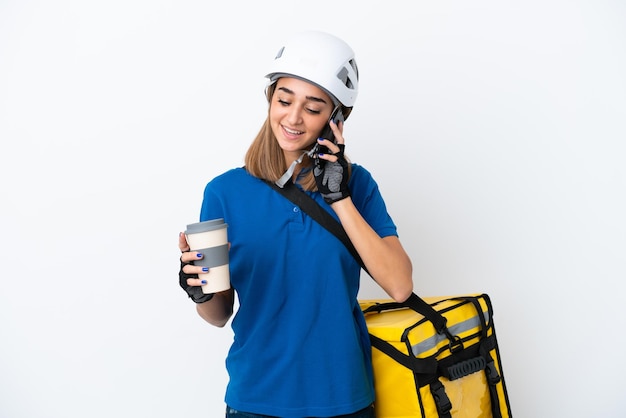 Junge kaukasische Frau mit Thermorucksack isoliert auf weißem Hintergrund mit Kaffee zum Mitnehmen und einem Handy