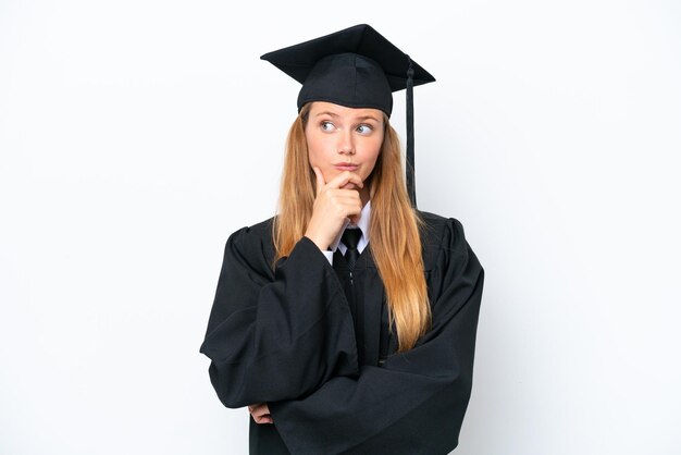 Foto junge kaukasische frau mit universitätsabschluss isoliert auf weißem hintergrund mit zweifeln und verwirrtem gesichtsausdruck