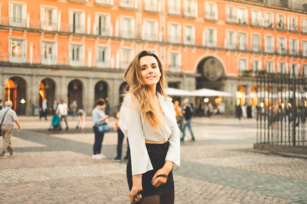 Junge kaukasische Frau Porträt mit einer weißen Bluse und einem schwarzen Rock an der Plaza Mayor in Madrid, Spanien.