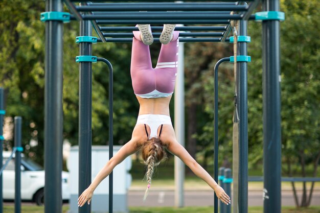 Junge kaukasische Frau trainiert auf dem Spielplatz im Freien. Fitness-Open-Air-Fitness-Workout-Outdoor-Konzept.