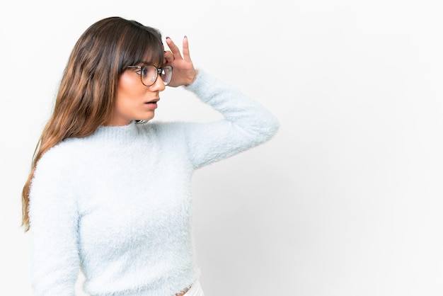 Foto junge kaukasische frau über einem isolierten weißen hintergrund mit überraschtem ausdruck, während sie zur seite schaut