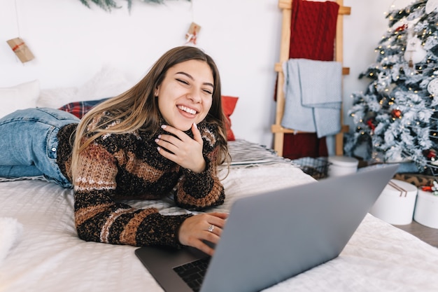 Junge kaukasische Frau wünscht frohe Weihnachten per Videoanruf mit Laptop