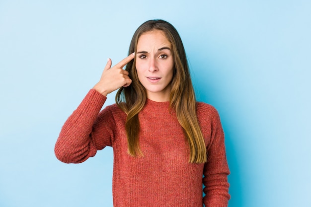 Junge kaukasische Frauenaufstellung lokalisiert, eine Enttäuschungsgeste mit dem Zeigefinger zeigend.