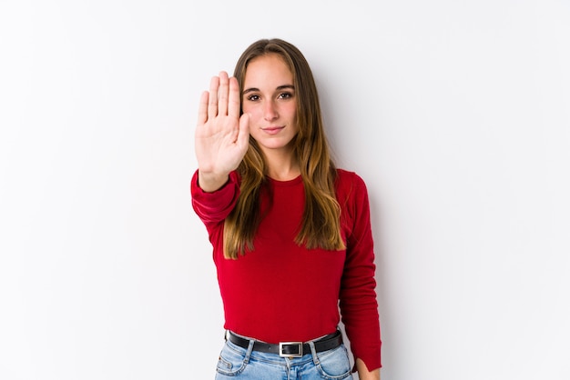 Junge kaukasische Frauenaufstellung lokalisierte Stellung mit der ausgestreckten Hand, die das Stoppschild zeigt und verhinderte Sie.