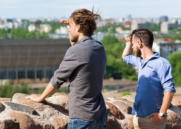 Junge kaukasische Freunde, die die Skyline der Stadt als Reise- und Freundschaftskonzept in die Ferne blicken