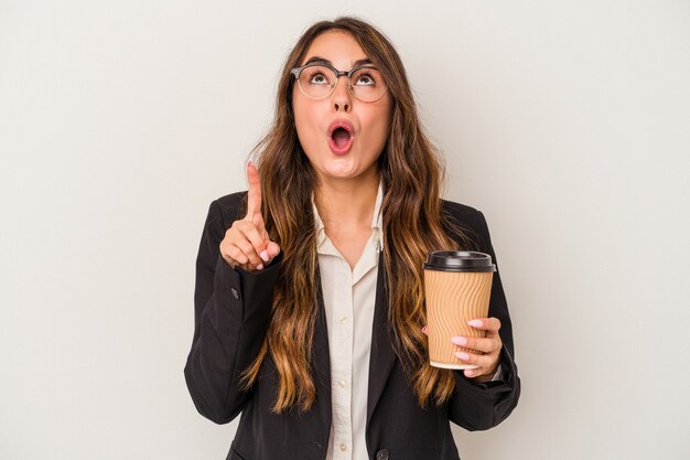 Junge kaukasische Geschäftsfrau, die einen Kaffee zum Mitnehmen lokalisiert auf weißem Hintergrund hält, der oben mit geöffnetem Mund zeigt.