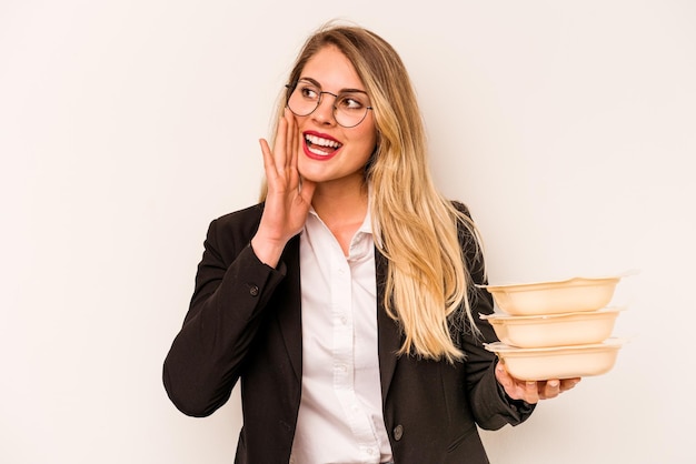 Junge kaukasische Geschäftsfrau, die Tupperware isoliert auf weißem Hintergrund hält, schreit und Handfläche in der Nähe des geöffneten Mundes hält