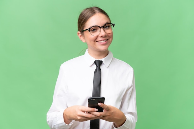 Junge kaukasische Geschäftsfrau über isoliertem Hintergrund, die eine Nachricht mit dem Handy sendet