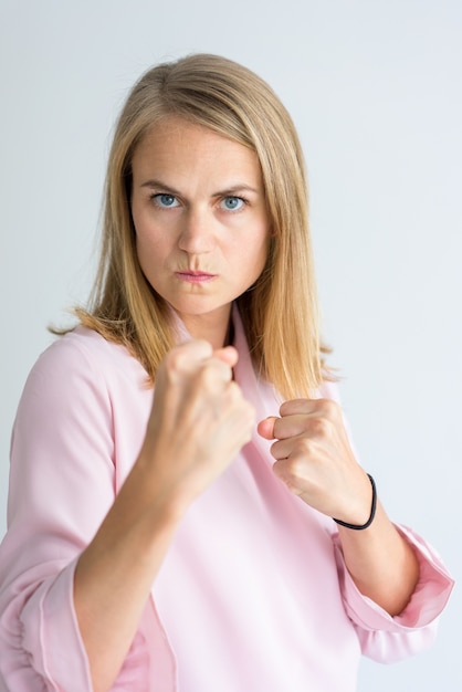 junge kaukasische Geschäftsfrau, welche die rosa Bluse steht in der Verpackenposition trägt.